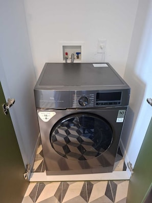 Eine kompakte, moderne Waschmaschine mit Bedienfeld, einer Leistungsaufkleber für 15 Kilogramm Fassungsvermögen und einem 1C-Garantie-Aufkleber.