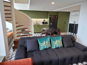 A modern living room with a sofa, a staircase, a kitchen area, and a dining table. - Junto a la histórica Muralla del Baluarte | 1BR + 2BA | Hasta 6 huéspedes (Panamá)