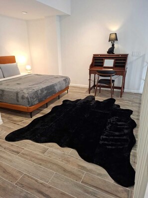 A bedroom with a bed, a desk, a chair, and a black fur rug. - Junto a la histórica Muralla del Baluarte | 1BR + 2BA | Hasta 6 huéspedes (Panamá)