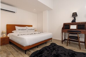 Ein Hotelzimmer mit einem Bett, einem Schreibtisch, einem Stuhl, einer Lampe und einem schwarzen, flauschigen Teppich.