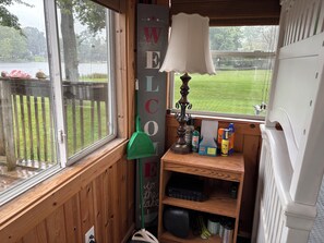 Una habitación con ventana, un cartel de bienvenida, una lámpara y un estante con productos de limpieza.