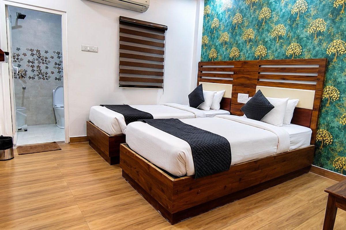 Cama doble con cabecera de madera, dos mesitas de noche, zona de ducha y pared con diseño.
