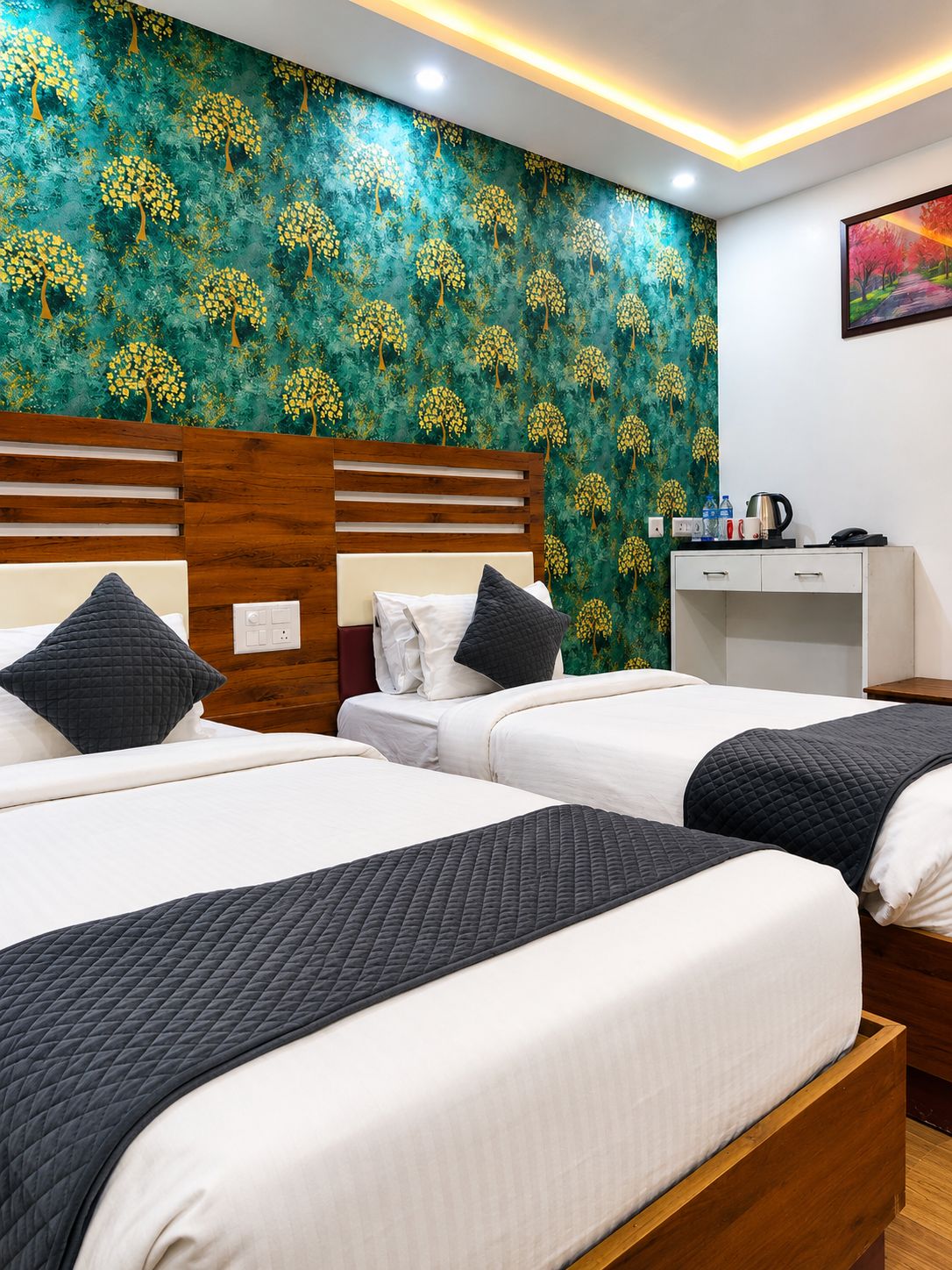 A hotel room with two beds, a wooden headboard, a nightstand, a desk, and a wall with a tree pattern.