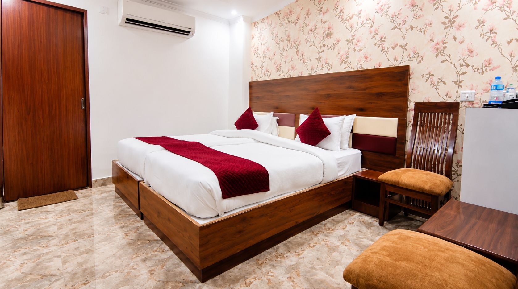 A hotel room with a wooden bed, a nightstand, a chair, and a desk.