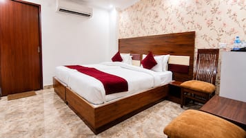 Une chambre d’hôtel avec un lit en bois, une table de chevet, une chaise et un bureau.
