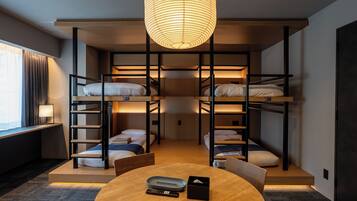 Quarto com beliche, mesa redonda, luminária e janela com cortinas.