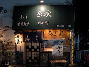 A restaurant with a dark facade, illuminated signage, and traditional Japanese decor.