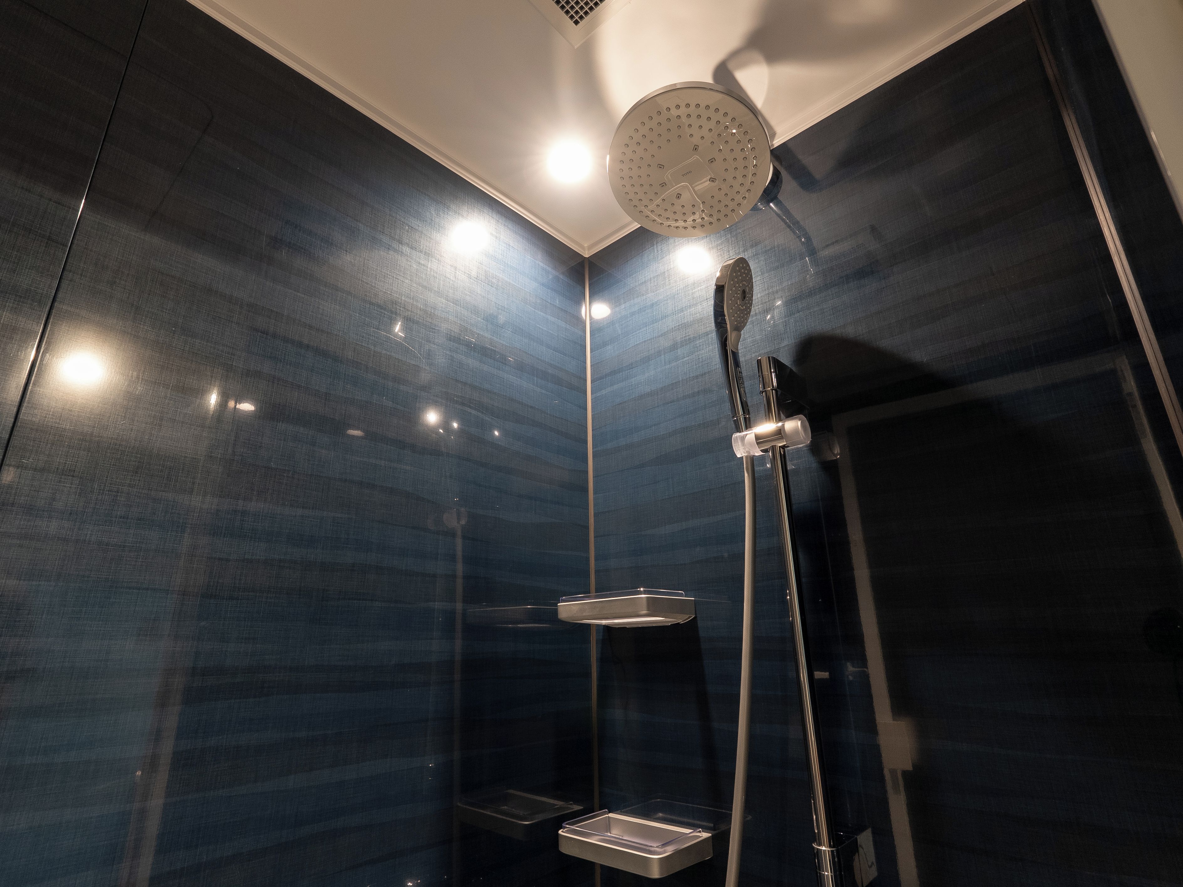 A modern bathroom with a shower, a mirror, and a light fixture.