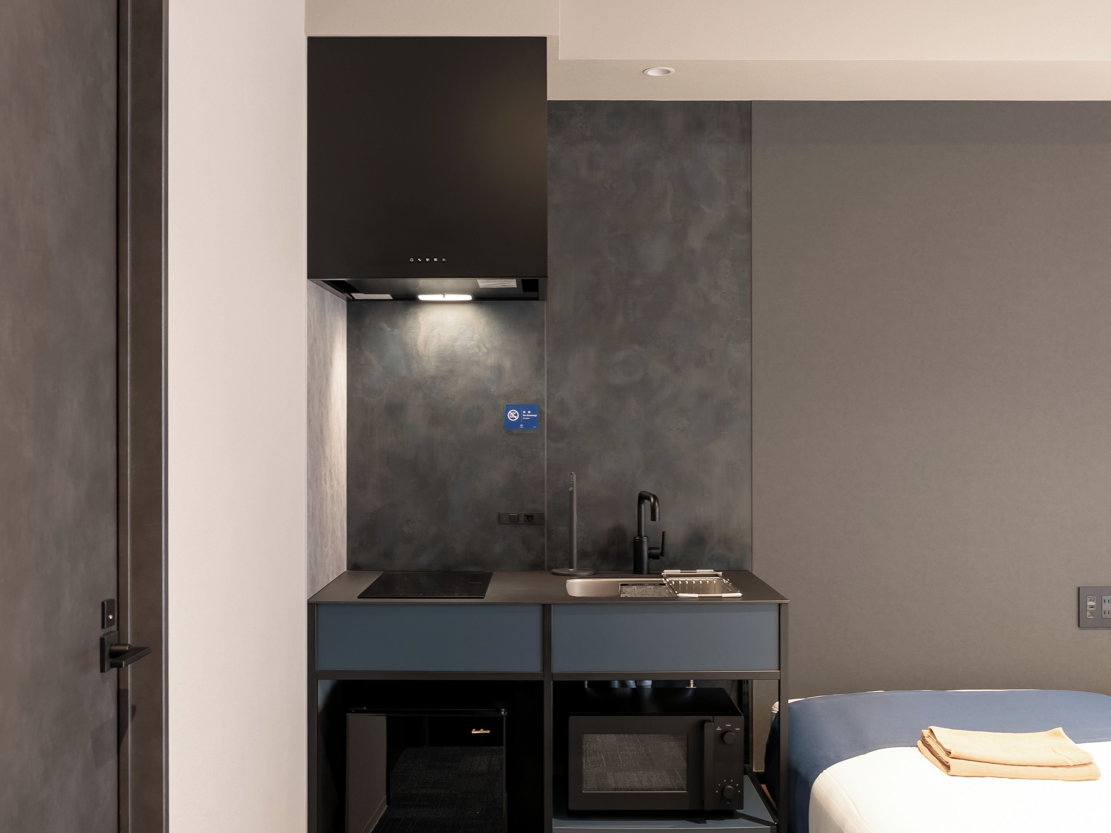 A modern kitchenette with a built-in microwave, a sink, and a stove.