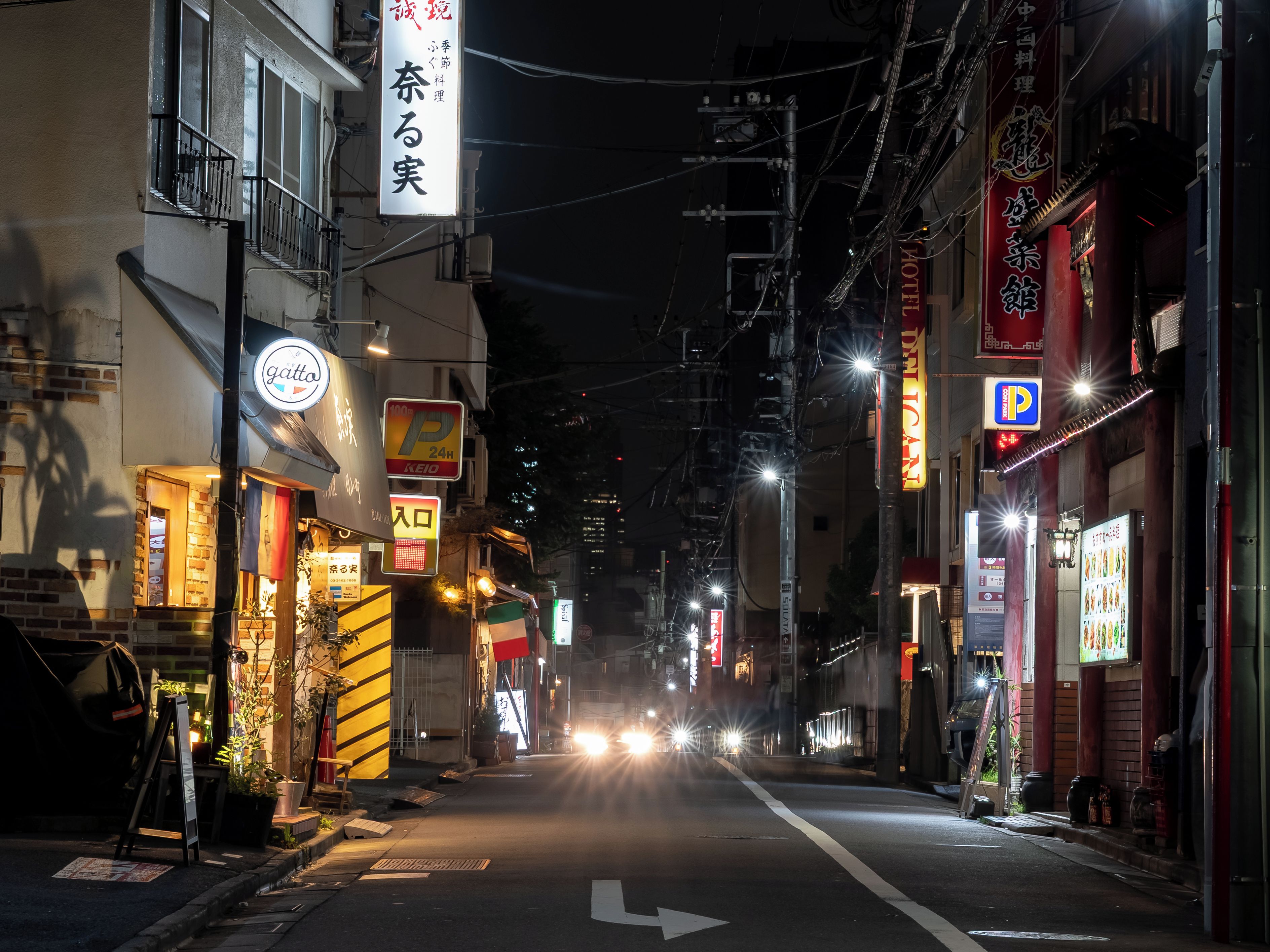 A nighttime street view with illuminated signs, a clear road, and a visible arrow indicating a one-way direction.