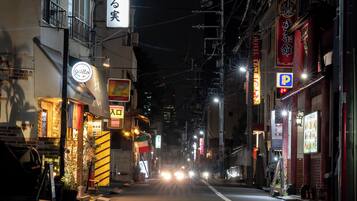 A nighttime street view with illuminated signs, a clear road, and a visible arrow indicating a one-way direction.