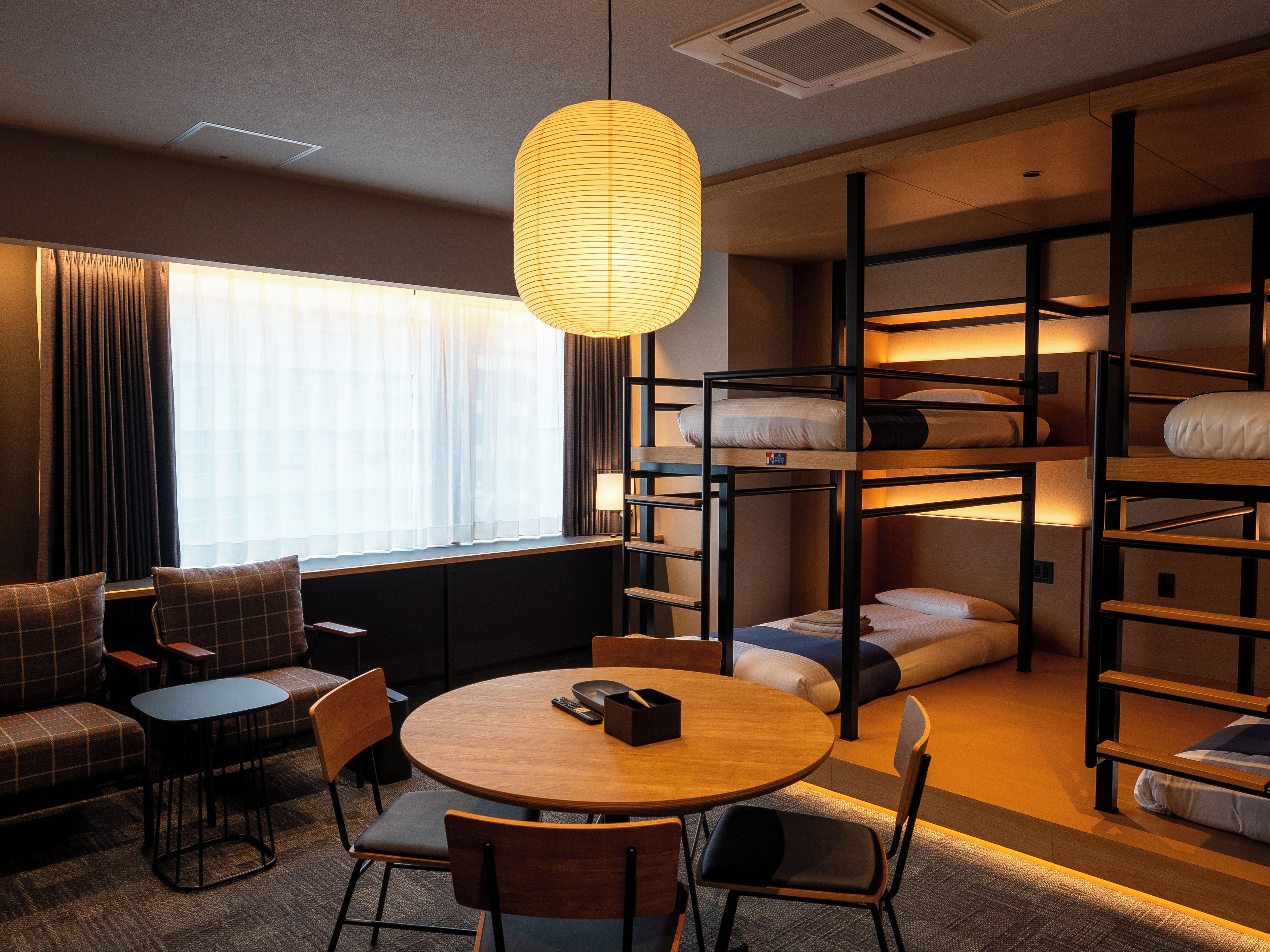 Una habitación de hotel moderna con literas, una mesa redonda para comer y un sofá.