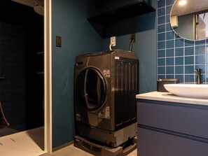 Un baño moderno y compacto con lavadora y secadora integradas, un lavabo y un espejo.