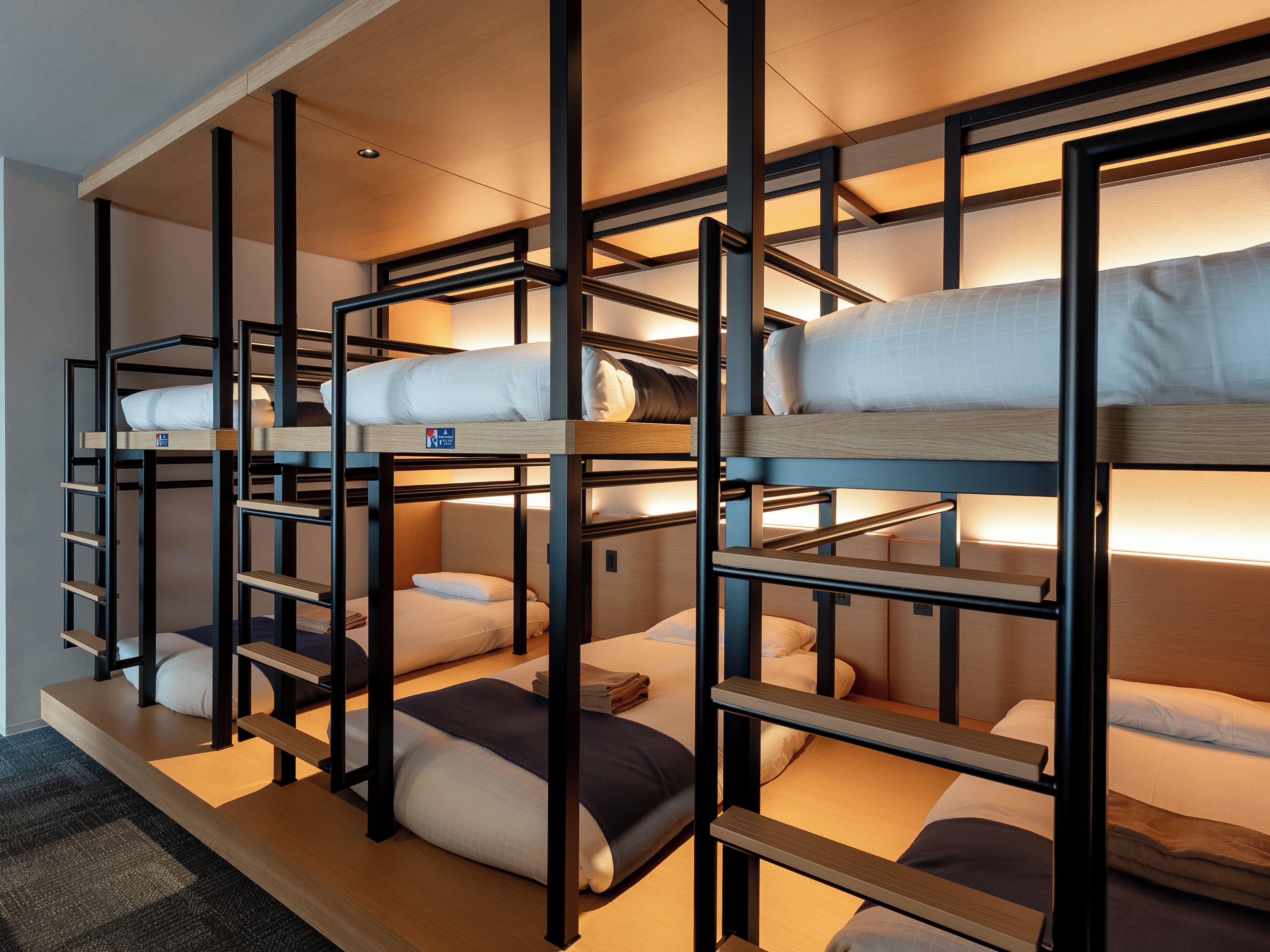 A bunk bed room with multiple levels, wooden railings, and a carpeted floor.