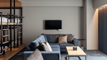 A modern living room with a sofa, a coffee table, a TV mounted on the wall, and a bunk bed structure.