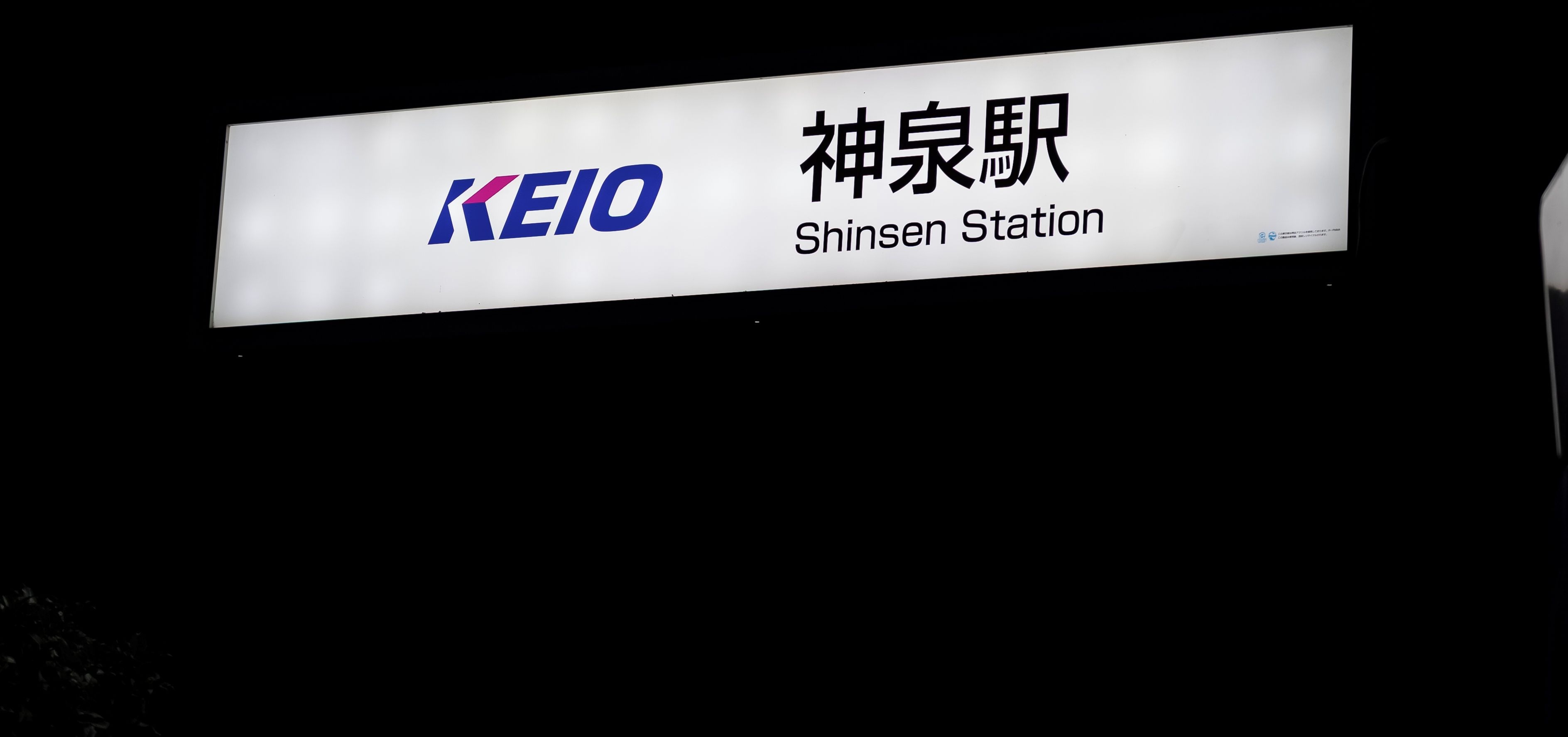 A sign with the KEIO logo and the name 'Shinsen Station' in both English and Japanese.