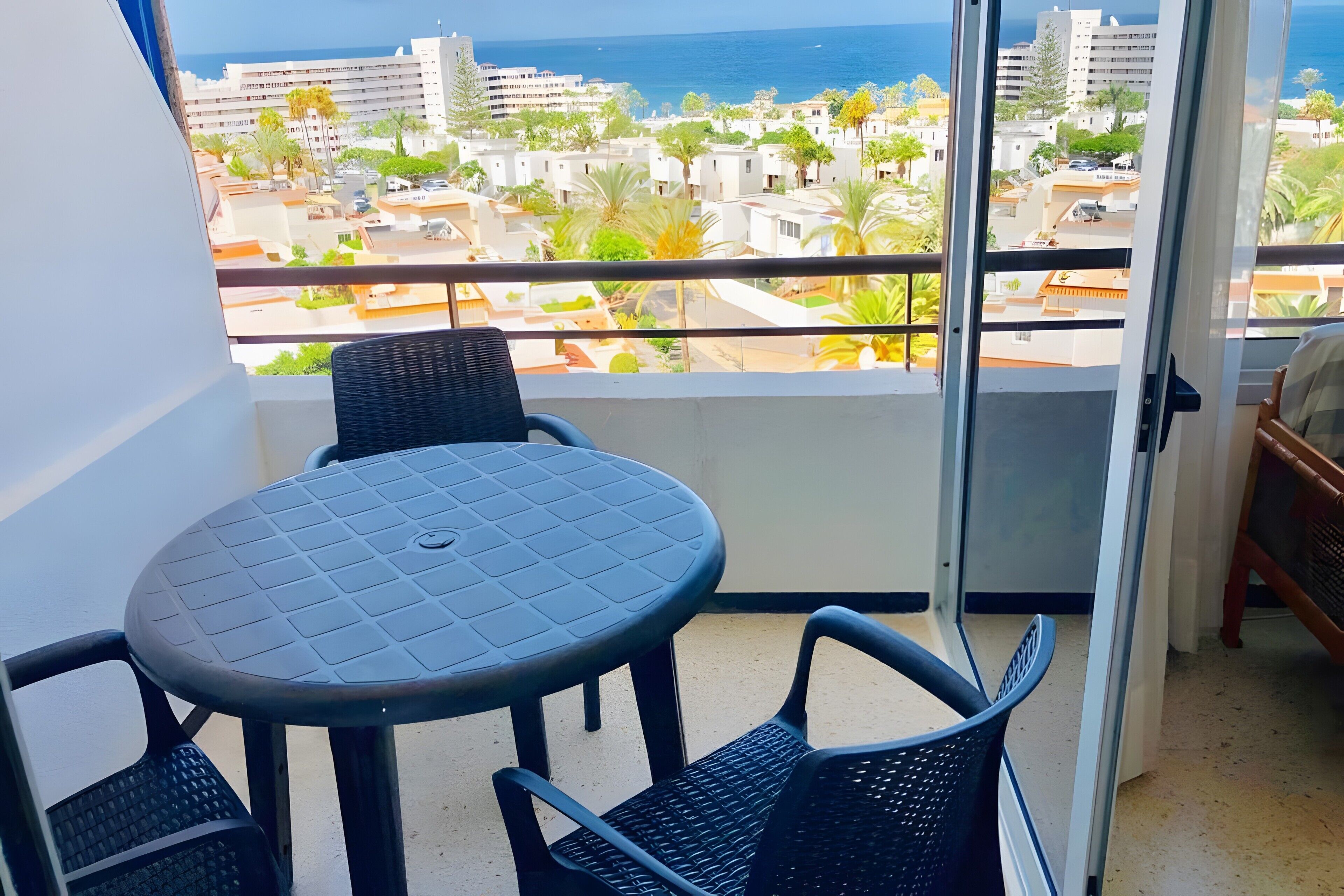 Een balkon met een tafel en stoelen, met uitzicht op een woongebied aan de kust.