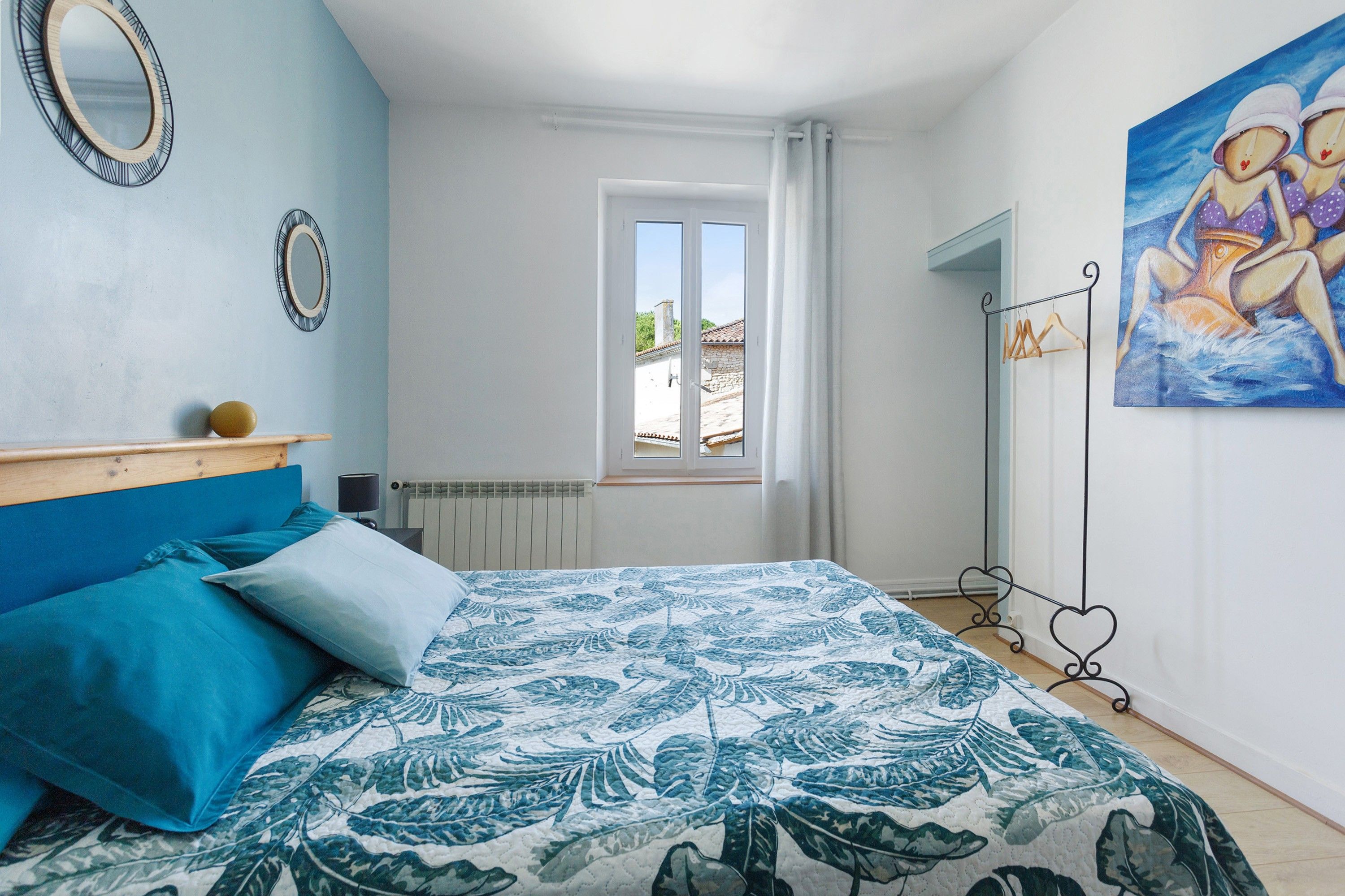 Une chambre à coucher avec un lit, une fenêtre, un radiateur et un tableau accroché au mur.