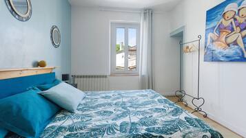 Une chambre à coucher avec un lit, une fenêtre, un radiateur et un tableau accroché au mur.