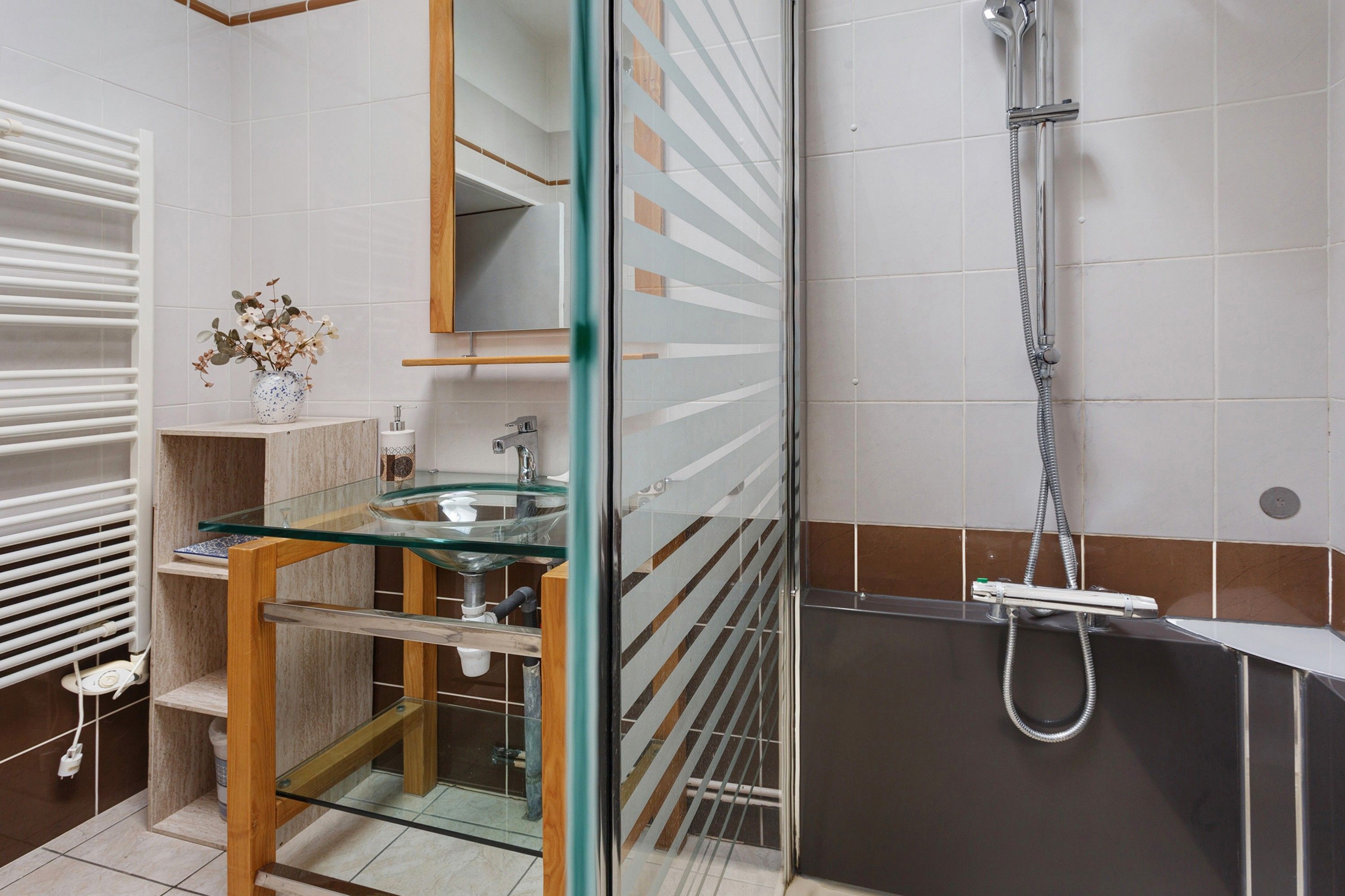 Une salle de bain moderne avec une douche à parois de verre, un lavabo doté d’un plan de travail en marbre et un porte-serviettes.