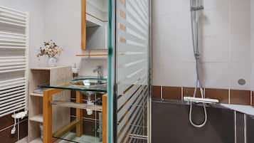 Une salle de bain moderne avec une douche à parois de verre, un lavabo doté d’un plan de travail en marbre et un porte-serviettes.