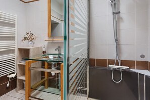 Ein modernes Badezimmer mit einer Duschkabine, einem Waschbecken mit Marmorplatte und einem Handtuchhalter.