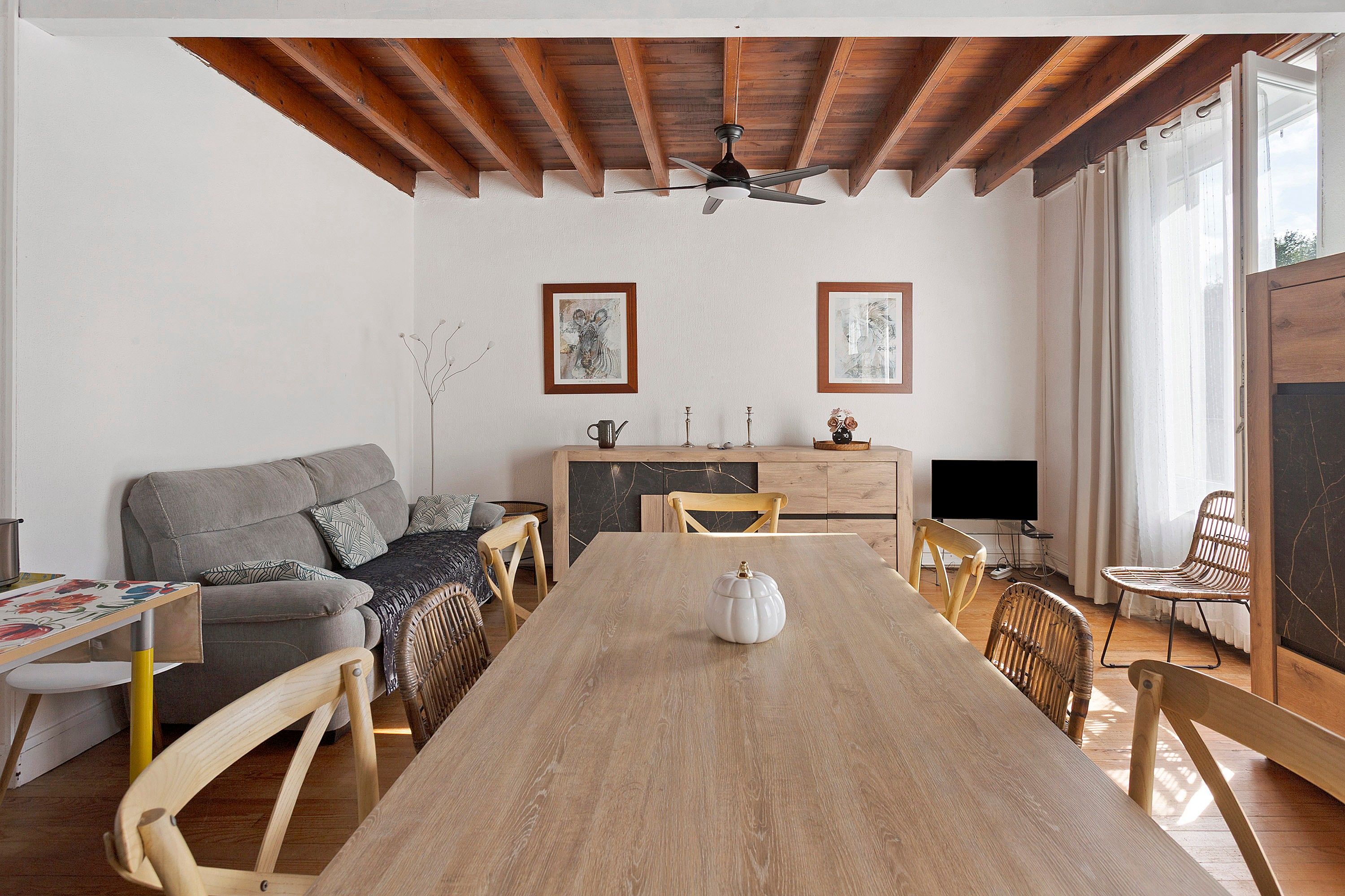 Un vaste espace de vie comprenant une table à manger en bois, un canapé et un téléviseur.
