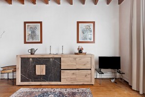 A room with a wooden cabinet, two framed artworks on the wall, a television, and a patterned rug.