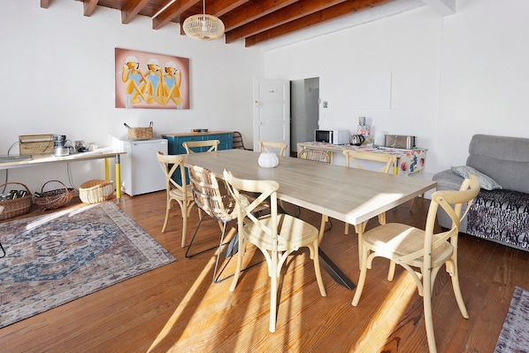 A dining area with a wooden table and chairs, a kitchen area with a microwave and stove, and a sofa.