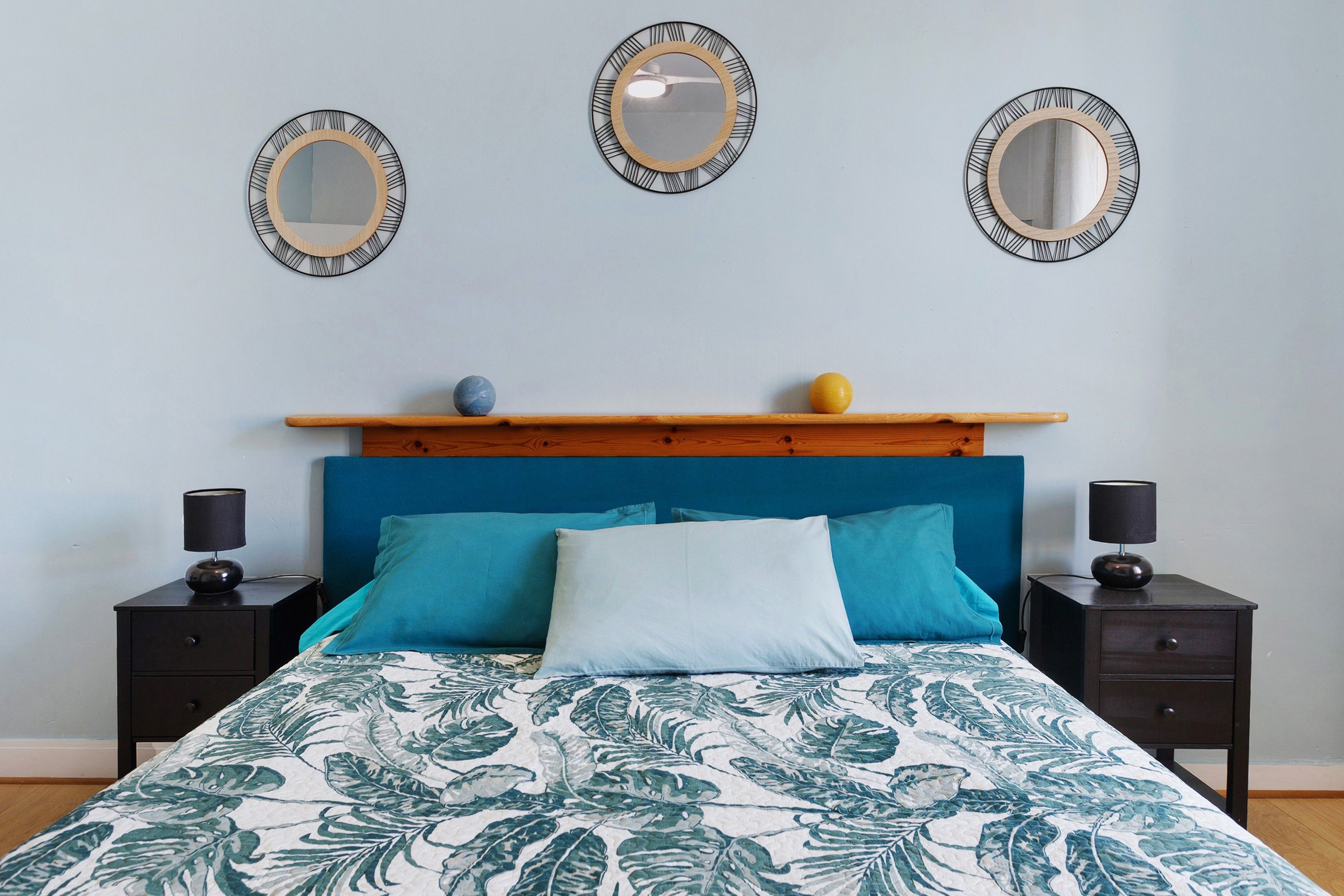 Ein Schlafzimmer mit einem Bett, zwei Nachttischen, einem Kopfteil und drei Wandspiegeln.