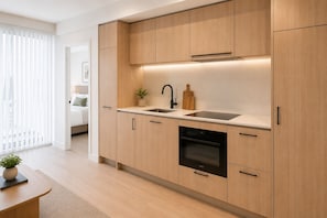 Eine moderne Küche mit hellen Holzschränken, einer schwarzen Spüle und einem eingebauten Backofen.