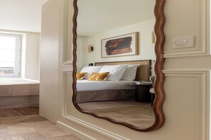 A bedroom with a bed, bedside table, and a large mirror.
