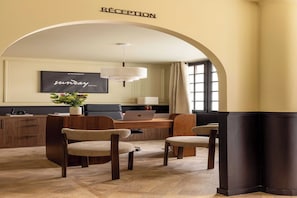 Een receptiezone met een checkmyguest bord, een receptiebalie, twee stoelen, een laptop, een potplant en een groot raam.