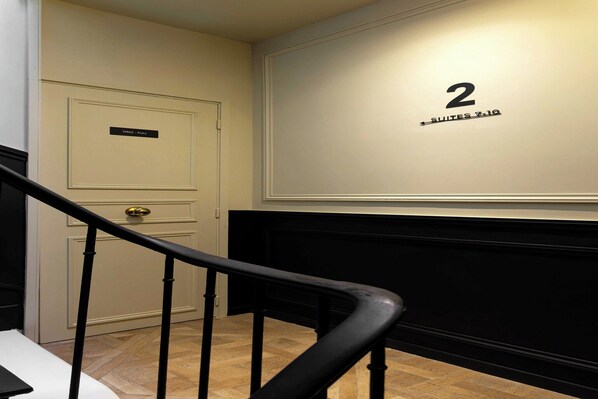 A hotel room with a white door, a black handrail, and a wall with the number '2' indicating the room number.
