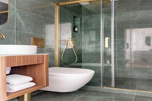 Een moderne badkamer met een wit toilet, een houten wastafelmeubel en een douchecabine met glazen wanden.