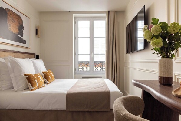 Een hotelkamer met een bed, een bureau, een stoel, een televisie en een raam met gordijnen.