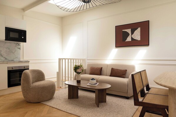 Een moderne woonkamer met een bank, fauteuil, salontafel en een eethoek met stoelen.