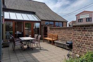 A patio with a table and chairs, a wooden bench, and a barbecue grill. - Duplex stay at the Alfonsine Farm (Horpmaal)