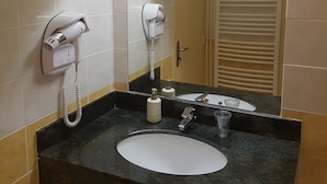 A bathroom with a white sink, a mirror, and two hair dryers mounted on the wall.