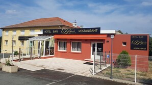 A hotel bar and restaurant named 'La Delicence' with a red facade and a yellow building in the background.