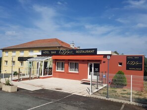 A hotel bar and restaurant named 'La Delicence' with a red facade and a yellow building in the background. - La Diligence HOTEL (Le Brignon)