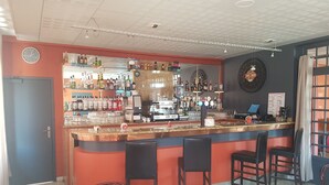 A bar area with a counter, chairs, and a coffee machine.