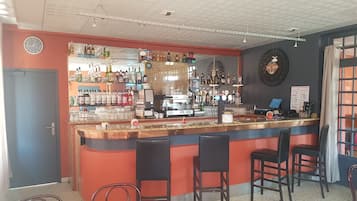 A bar area with a counter, chairs, and a coffee machine.