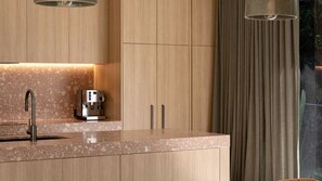 Eine moderne Küche mit integrierter Kaffeemaschine, einer Arbeitsplatte aus Granit und Holzschränken.