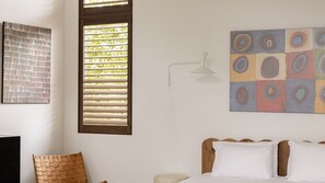 Ein Schlafzimmer mit einem Bett, einer Wandlampe und einem Fenster mit Jalousien.