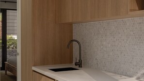 Une cuisine moderne avec des meubles en bois et un évier agrémenté d’un dosseret en carreaux hexagonaux.