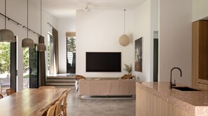 Une cuisine moderne dotée d’un grand îlot central, d’un coin repas avec une table en bois et d’un espace de vie avec un canapé.
