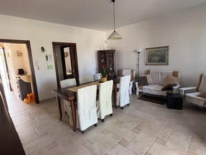 Ein Essbereich mit Tisch, Stühlen, einem Schrank, einer Couch und einem Bild an der Wand.
