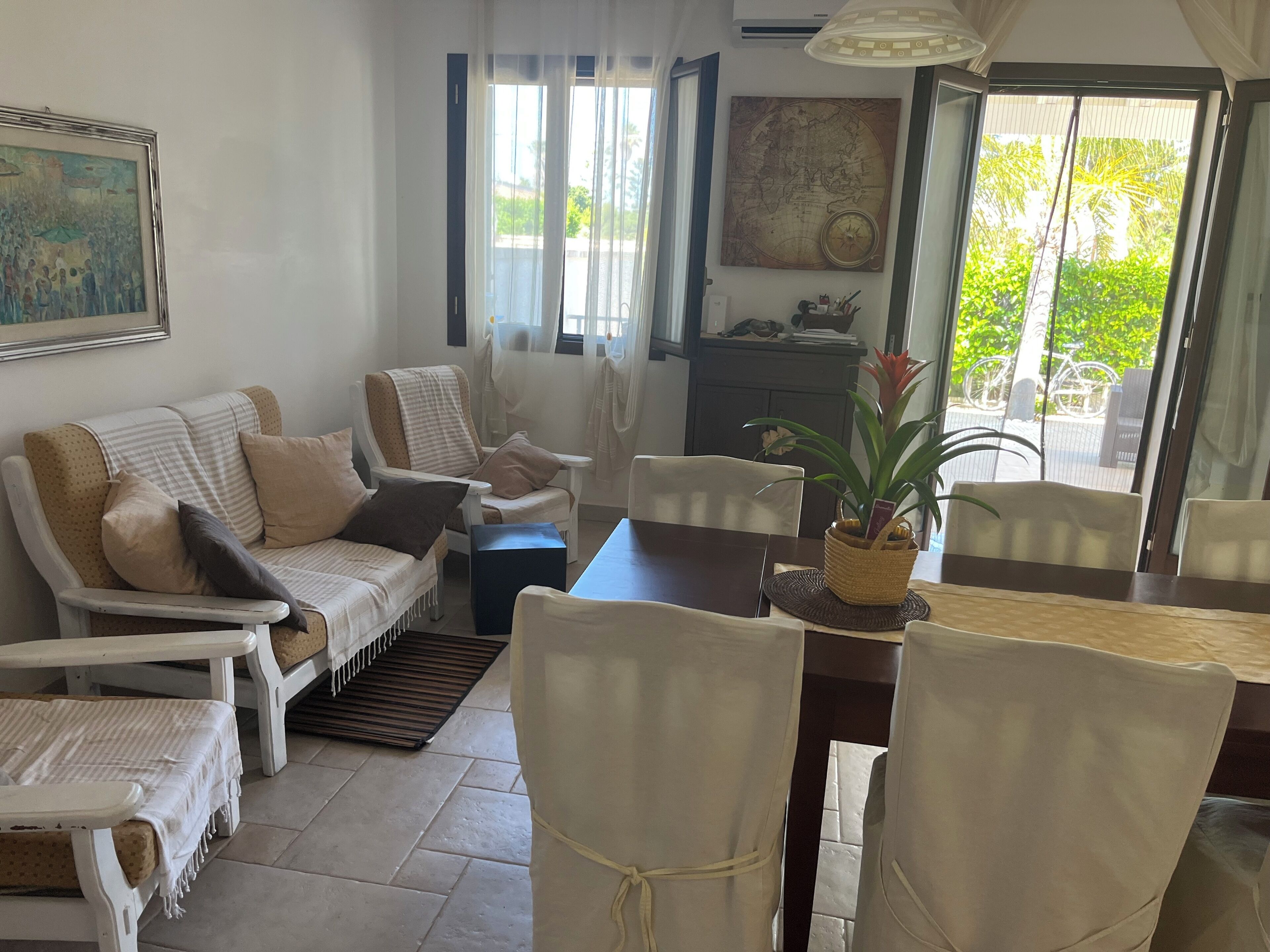 Una sala de estar con sofá, sillas, una mesa de comedor y una planta en maceta.