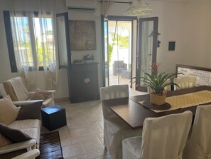 Ein modernes Wohnzimmer mit einer Couch, einem Esstisch und Blick ins Freie.